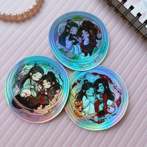 May include: Three circular holographic stickers featuring chibi-style anime characters in pairs. Each sticker displays two figures with long dark hair, dressed in traditional robes, surrounded by floral elements, bamboo, and small animals like rabbits.