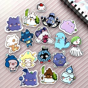 Puede incluir: Una colección de pegatinas coloridas troqueladas con varios personajes de dibujos animados. Las pegatinas muestran una variedad de diseños, incluyendo criaturas lindas con expresiones y poses únicas. Las pegatinas están dispuestas sobre una superficie a rayas rosas y blancas.