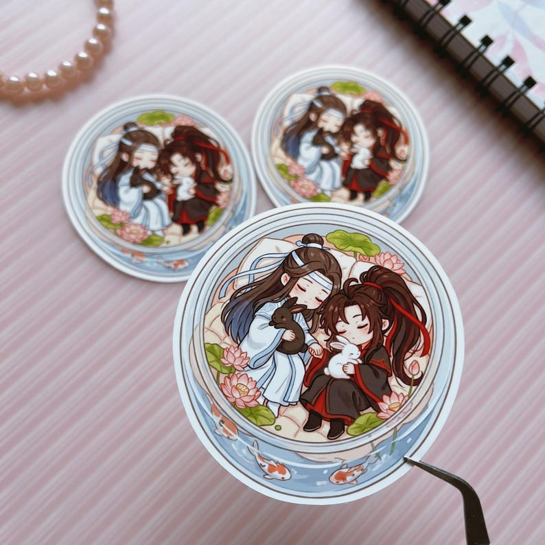 May include: Three circular stickers featuring a chibi-style illustration of two characters with long hair, one in white and blue robes and one in black and red robes, each holding a small rabbit amidst pink lotus flowers and koi fish in water.
