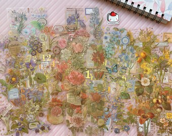 May include: A sheet of transparent stickers with a floral theme. The stickers feature various flowers, butterflies, numbers, and text in gold and blue tones. The stickers are perfect for adding a touch of vintage charm to journals, planners, and other craft projects.