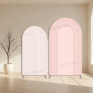 Può includere: Due pannelli di sfondo ad arco, uno rosa chiaro e uno bianco, con un design a righe verticali. I pannelli hanno una parte superiore arrotondata e sono supportati da piccole gambe di metallo. Il testo "The 9 trees" è visibile.