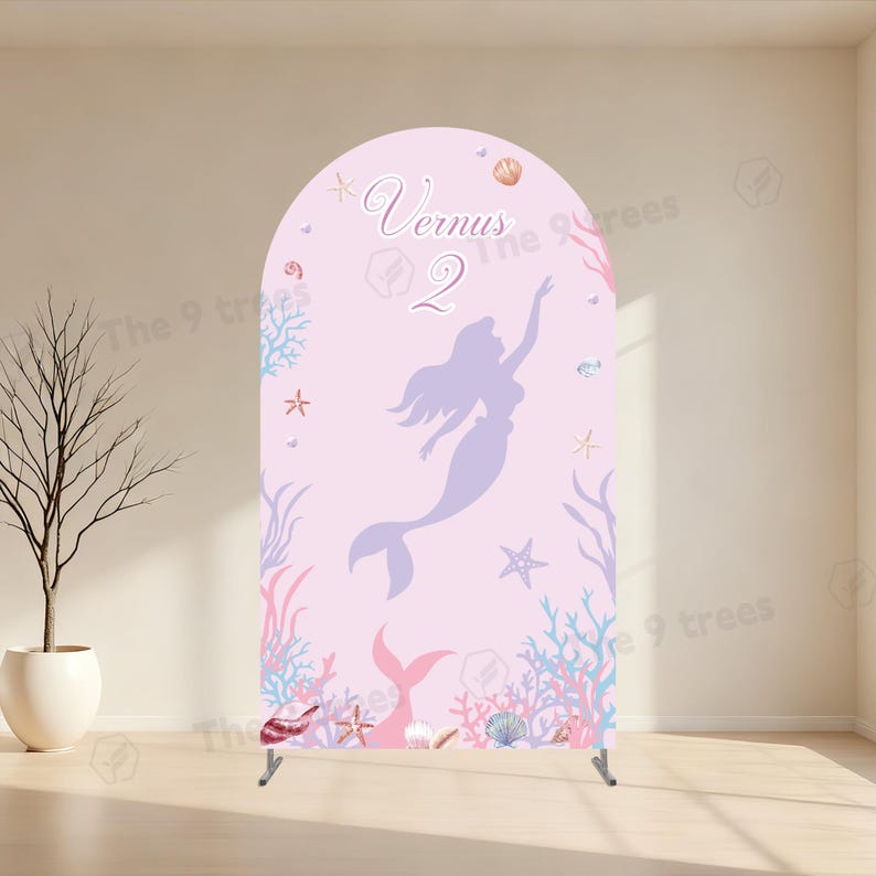 May include: An arched backdrop display featuring a light pink background with a purple mermaid silhouette, the text "Vernus" and "2", and various illustrations of coral, starfish, and seashells along the bottom and sides of the panel.