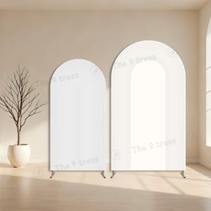 Peut inclure: Deux panneaux décoratifs blancs en forme d'arche avec un design minimaliste. L'un présente des lignes verticales, l'autre un espace central ouvert. Les deux ont un sommet incurvé et sont soutenus par de petits pieds en métal. Le texte "The 9 trees" est visible.