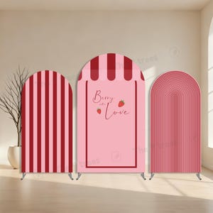 Pode incluir: Três painéis decorativos arqueados em tons de rosa e vermelho. O painel central tem o texto "Berry in Love" com ilustrações de morangos. Os painéis são suportados por suportes metálicos e apresentam listras verticais e um topo curvo.