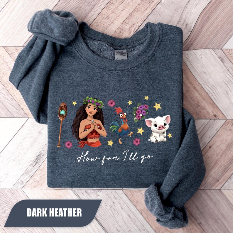Pu&ograve; includere: Felpa blu melange scuro con una grafica a cartoni animati di una donna, un gallo, un maiale e stelle. Il testo "How far I'll go" &egrave; sotto la grafica. La parte inferiore della felpa ha il testo "DARK HEATHER".
