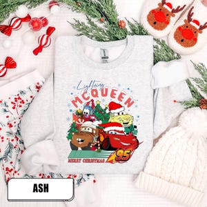 May include: Ash-colored sweatshirt featuring a colorful graphic of Lightning McQueen and other Cars characters in Santa hats, with the text "Lightning McQueen" and "Merry Christmas". The number 95 is also visible.