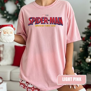 Może przedstawiać: Jasnor&oacute;żowa koszulka Spider-Man z napisem "Spider-Man Brand New Day" w kolorze czerwonym i niebieskim. Koszulka wykonana jest z miękkiego, wygodnego materiału. Koszulka jest jasnor&oacute;żowa.