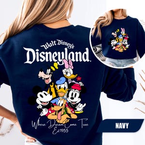 May include: A navy blue crewneck sweatshirt featuring a large white graphic on the back that reads Walt Disney's Disneyland Where Dreams Come True Est 1955, with colorful illustrations of Mickey, Minnie, Donald, Daisy, Goofy, and Pluto.