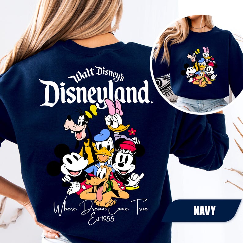 May include: A navy blue crewneck sweatshirt featuring a large white graphic on the back that reads Walt Disney's Disneyland Where Dreams Come True Est 1955, with colorful illustrations of Mickey, Minnie, Donald, Daisy, Goofy, and Pluto.