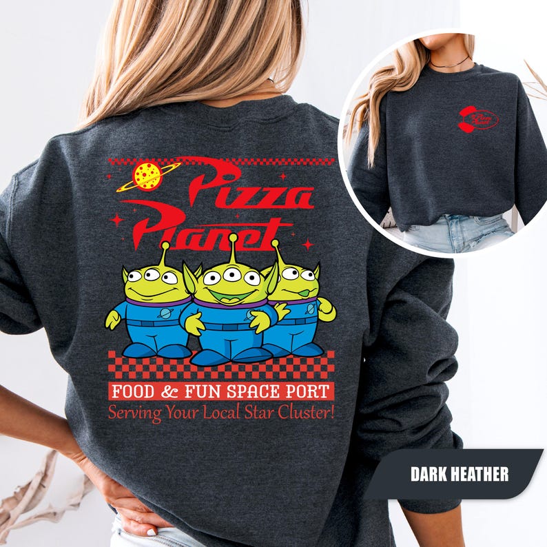Puede incluir: Sudadera gris oscuro con el logo de Pizza Planet y tres personajes alien&iacute;genas verdes con uniformes azules. La parte trasera de la sudadera tiene el texto "FOOD & FUN SPACE PORT Serving Your Local Star Cluster!" en rojo y blanco.