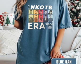 Puede incluir: Camiseta azul vaquero con el texto "IN MY NKOTB ERA since '89". La camiseta presenta una cuadrícula de nueve imágenes de los miembros de la banda. La camiseta es de corte holgado.