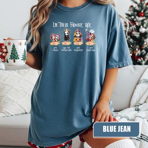 May include: Blue jean colored t-shirt with the text "IN THIS HOUSE WE" above four cartoon characters. Below the characters are the words "LOVE FAMILY", "LOVE THE PUMPKIN KING", "LOVE HALLOWEEN", and "LOVE CHRISTMAS".