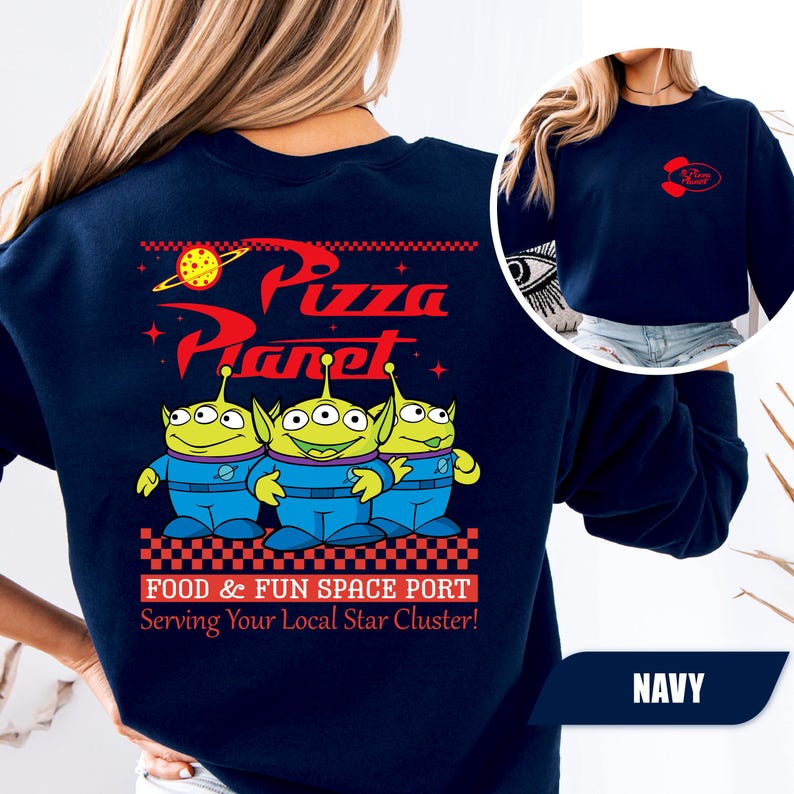 Puede incluir: Sudadera azul marino con el logo de Pizza Planet y tres personajes alien&iacute;genas verdes. El dise&ntilde;o trasero incluye el texto "FOOD & FUN SPACE PORT Serving Your Local Star Cluster!". Un logotipo m&aacute;s peque&ntilde;o de Pizza Planet est&aacute; en la parte delantera.