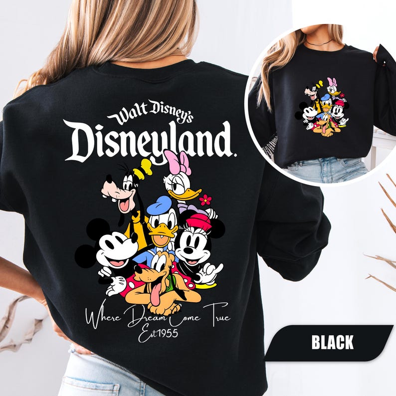 May include: A black crewneck sweatshirt featuring a large graphic on the back with the text Walt Disney's Disneyland Where Dreams Come True Est 1955 and a group of cartoon characters including Mickey, Minnie, Donald, Daisy, Goofy, and Pluto.