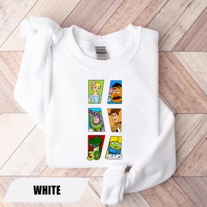 May include: A white crewneck sweatshirt featuring a graphic print of six Toy Story characters arranged in rectangular frames. The design includes Bo Peep, Mr. Potato Head, Buzz Lightyear, Woody, Rex, and an alien, with the text 30 YEARS.