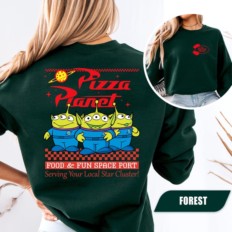 Puede incluir: Sudadera verde bosque con el logo de Pizza Planet y tres personajes alien&iacute;genas verdes con monos azules. La parte trasera de la sudadera tiene las palabras "Pizza Planet" en rojo, con la frase "Food & Fun Space Port" debajo.