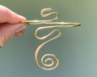 May include: Gold wire bracelet with a swirling design. The bracelet is open and adjustable.