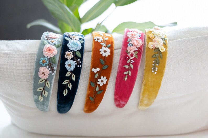May include: Five velvet headbands with embroidered floral designs. The headbands are in shades of blue, green, orange, pink, and yellow.