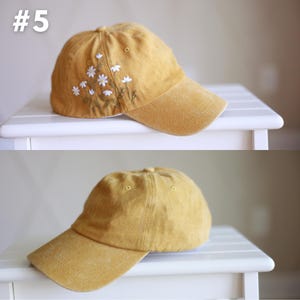 Peut inclure: Une casquette de baseball jaune moutarde avec un motif de broderie de marguerite blanche. La casquette a une visi&egrave;re incurv&eacute;e et une couronne structur&eacute;e.