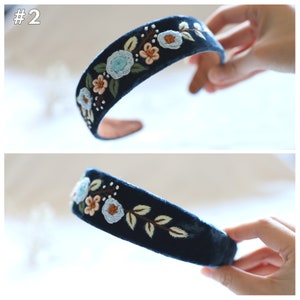 May include: A dark blue velvet headband with embroidered flowers in shades of blue, pink, and brown. The headband is shown from two angles.