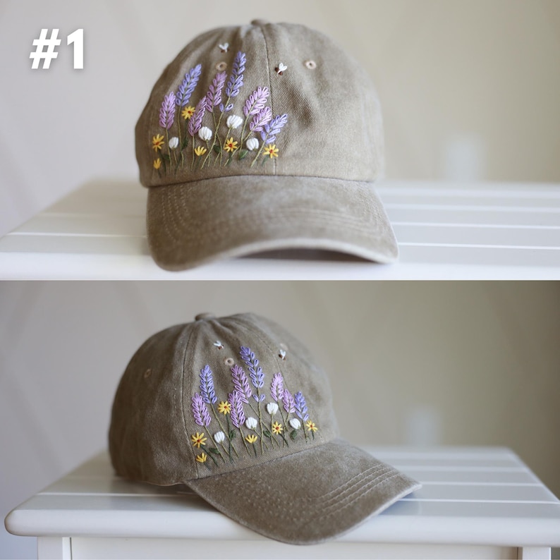 Peut inclure: Une casquette de baseball marron avec des fleurs brod&eacute;es de couleur violette, blanche et jaune. La casquette a une visi&egrave;re incurv&eacute;e et une sangle &agrave; l'arri&egrave;re.