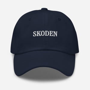 May include: A navy blue baseball cap with the word "SKODEN" embroidered in white on the front.