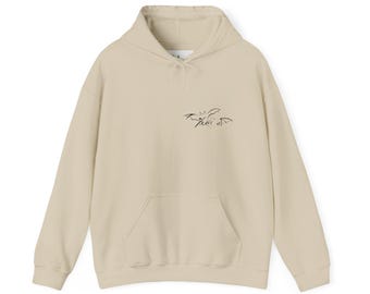 May include: A beige hoodie with a front pocket and a drawstring hood. The hoodie features a small, black graphic design on the upper chest. The garment is made of a soft, comfortable material.