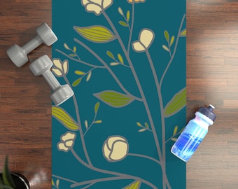 May include: A teal yoga mat with a floral pattern featuring white, yellow, and orange flowers. The mat is on a wooden floor with a water bottle and two dumbbells.