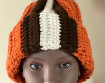 May include: A crocheted beanie hat with a brown, white, and orange striped pattern. The hat has a fluffy pom pom on top.