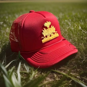 May include: A red and black trucker hat with a gold-colored emblem featuring a palm tree and the words "Out of Office".