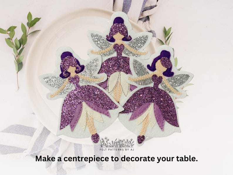 Pu&ograve; includere: Tre ornamenti di fata con glitter viola, ali bianche e sfondo bianco. Le fate indossano abiti viola e hanno i capelli viola.