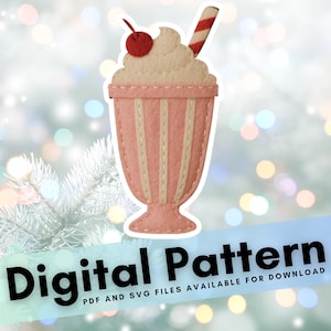 Puede incluir: Un diseño de batido de fieltro en rosa y crema, cubierto con crema batida, una cereza y una pajita a rayas. El texto "Digital Pattern" se muestra en una pancarta azul en la parte inferior de la imagen.