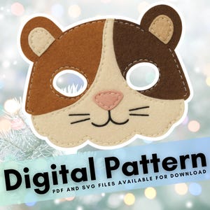May include: A handmade felt hamster mask in brown, beige, and pink. The mask has eye holes, a pink nose, and whiskers. The text "Digital Pattern" is displayed on a blue banner below the mask. PDF and SVG files are available for download.