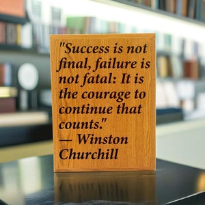 May include: A wooden plaque with a quote by Winston Churchill: "Success is not final, failure is not fatal: It is the courage to continue that counts."