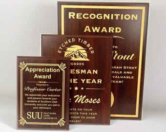 May include: Three wooden plaques with gold lettering. The top plaque reads "Recognition Award". The middle plaque reads "Etched Timber Awards" and features a mountain range graphic. The bottom plaque reads "Appreciation Award" and features the text "Presented to Professor Carter".