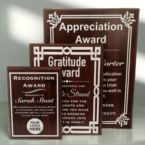 Może przedstawiać: Trzy drewniane tabliczki z białym tekstem i ozdobnymi ramkami. Górna tabliczka zawiera napis "Appreciation Award". Środkowa tabliczka zawiera napis "Gratitude Award", a dolna tabliczka zawiera napis "Recognition Award Presented to Sarah Stout".