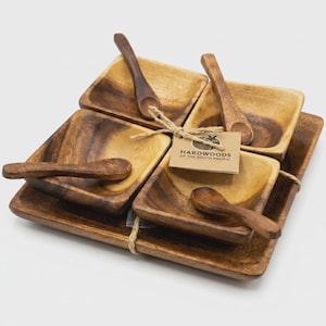 May include: A set of wooden serving bowls and spoons. The set includes four square bowls, four small spoons, and a rectangular tray, all made of a light brown wood. A tag reads "Hardwoods of the South Pacific".