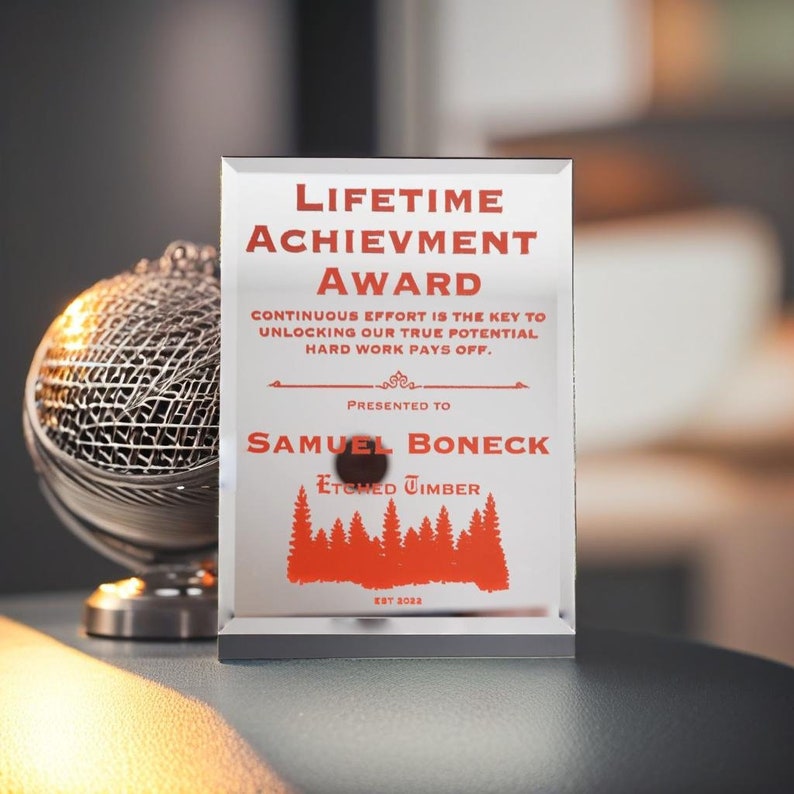Puede incluir: Un premio de vidrio rectangular con el texto "LIFETIME ACHIEVEMENT AWARD" en rojo. El premio se otorga a Samuel Boneck por Etched Timber. Tambi&eacute;n se incluye el texto "Continuous effort is the key to unlocking our true potential, hard work pays off".