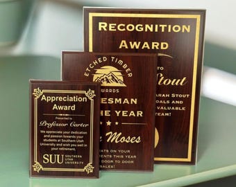 May include: Three wooden plaques with gold lettering. The top plaque says "Recognition Award". The middle plaque says "Etched Timber Awards" and features a mountain range graphic. The bottom plaque says "Appreciation Award" and "Presented to Professor Carter".