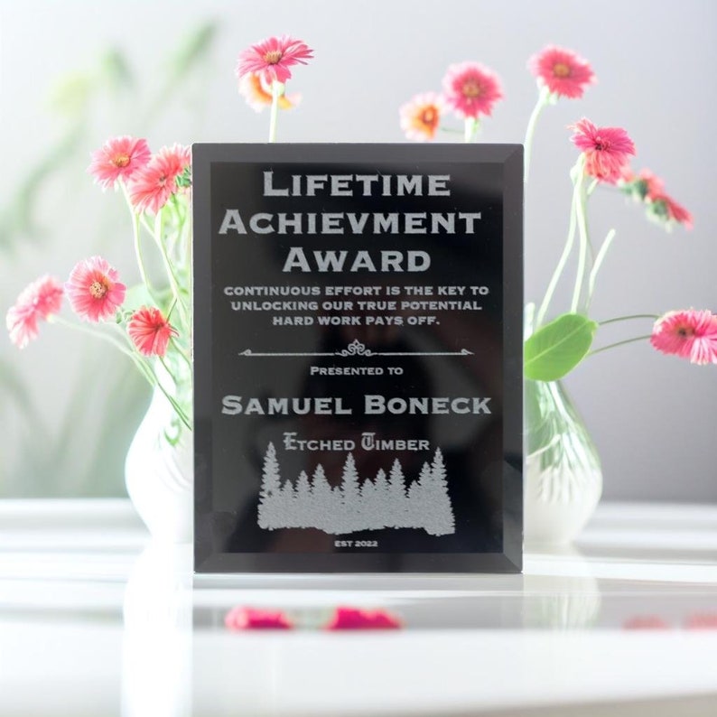 Pu&ograve; includere: Placca premio nera con lettere argentate. La placca recita "Lifetime Achievement Award", "Continuous effort is the key to unlocking our true potential. Hard work pays off."  "Presented to Samuel Boneck" e "Etched Timber Est 2022".
