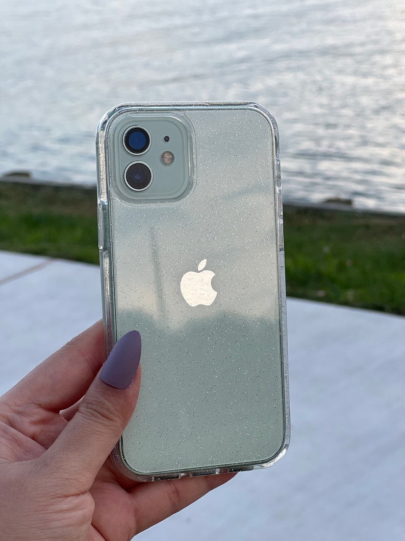 Op de afbeelding: Een transparante telefoonhoes met een lichtgroen glitterontwerp en een zilveren Apple-logo. De hoes is ontworpen voor een iPhone.