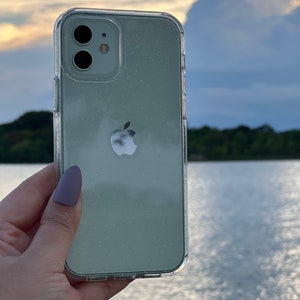 Op de afbeelding: Een transparante telefoonhoes met een lichtgroen glitterontwerp. De hoes heeft een verhoogde camerabult en het Apple-logo is zichtbaar op de achterkant.