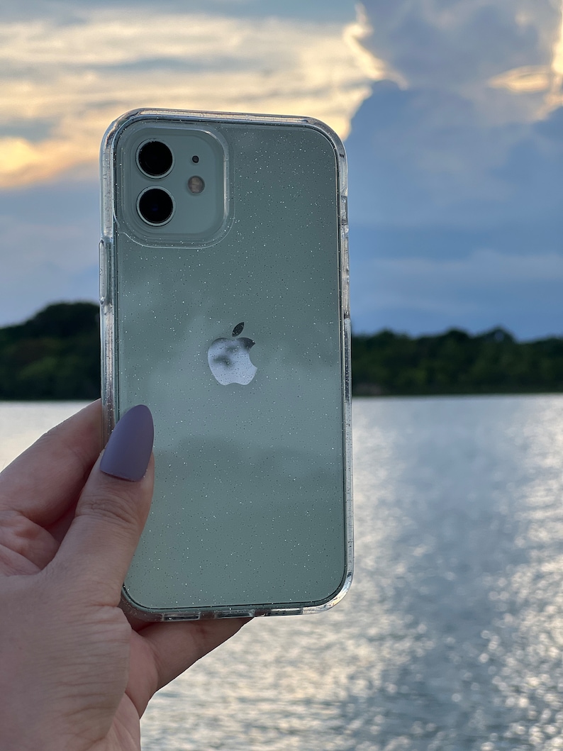 Op de afbeelding: Een transparante telefoonhoes met een lichtgroen glitterontwerp. De hoes heeft een verhoogde camerabult en het Apple-logo is zichtbaar op de achterkant.