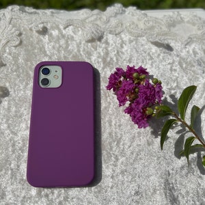 May include: Purple silicone phone case for an iPhone. The case is a solid color with no design.
