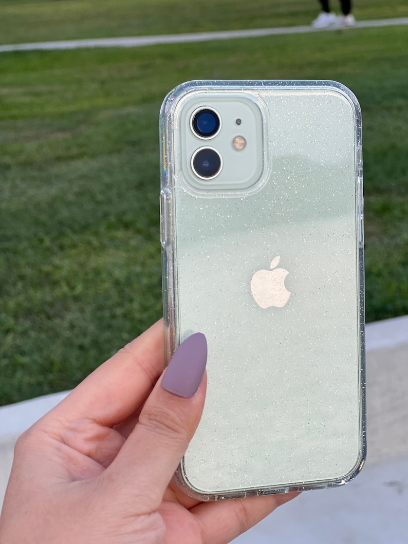 Op de afbeelding: Een transparante telefoonhoes met een lichtgroen glitterontwerp. De hoes heeft een verhoogde camerabult en een wit Apple-logo.