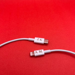 May include: Two white charging cables with different connectors. One cable has a USB-C connector with the text "ZK" on it. The other cable has a Lightning connector with the text "A.M." on it.