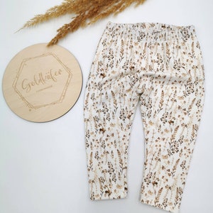 May include: White leggings with a brown floral print. The leggings have an elastic waistband.