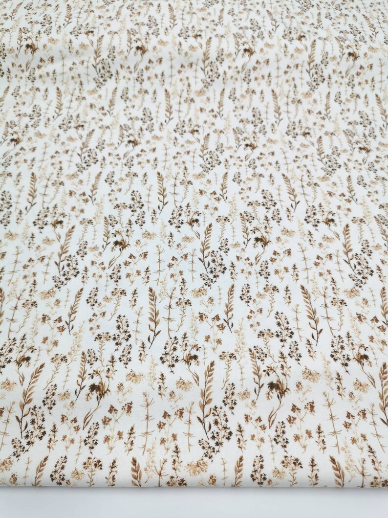 May include: White fabric with a brown floral pattern. The pattern features small, delicate flowers and leaves.