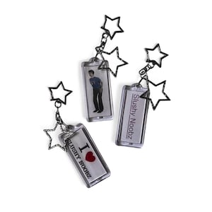May include: Three clear rectangular keychains with black star-shaped charms. One keychain has a photo of a person, another reads "Slushy Noobz", and the third says "I ❤️ Slushy Noobz".
