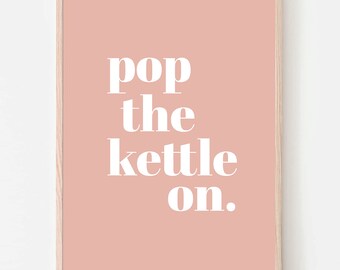 Peut inclure: Une affiche murale rectangulaire dans un cadre en bois clair présentant un fond rose poudré avec le texte blanc pop the kettle on. La typographie est en gras et centrée, créant un contraste net avec le fond de couleur unie.